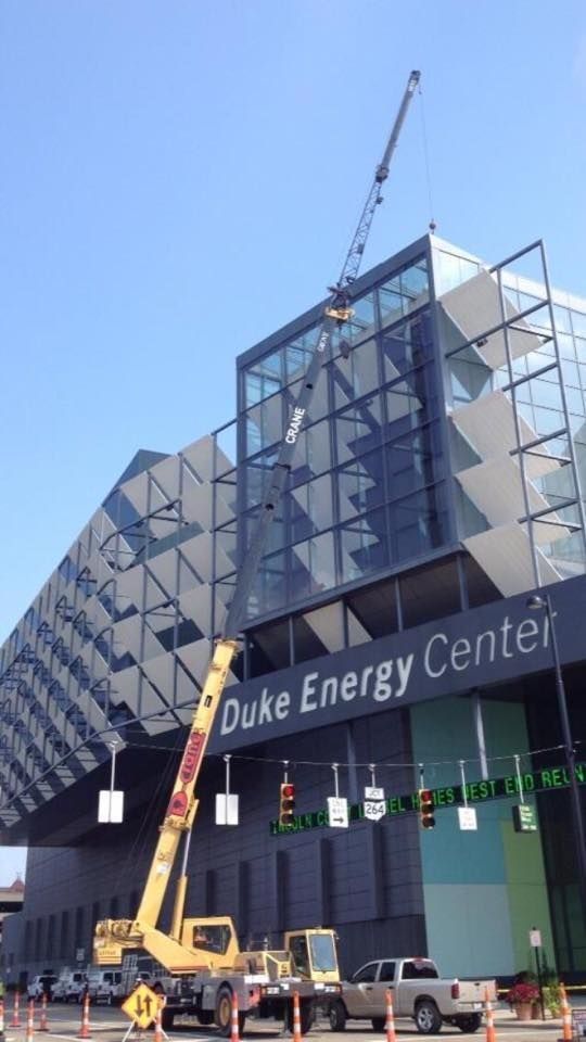 Crane lifting material near the Duke Energy Center. Blue sky, modern building, construction.