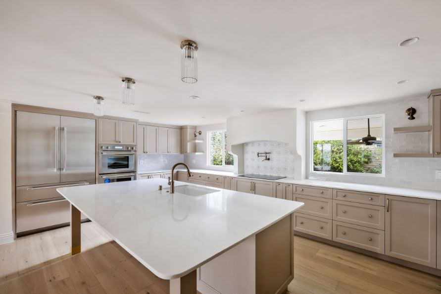 Bright modern kitchen with a large white island, stainless appliances, and light wood cabinets