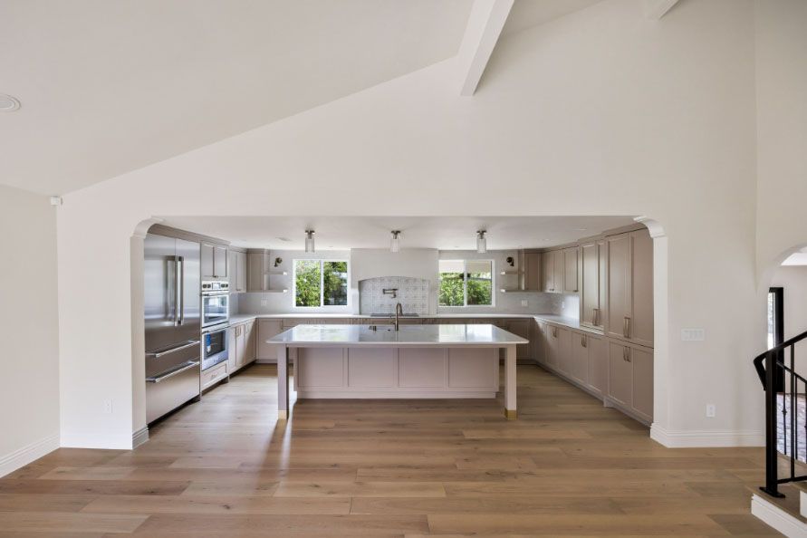 Bright open kitchen with white cabinetry, large island, and wooden floors