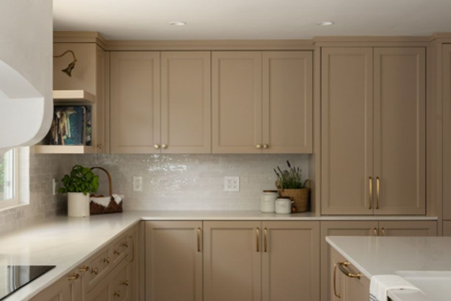 Modern beige kitchen with built-in cabinets, white countertop, and potted plants by the window