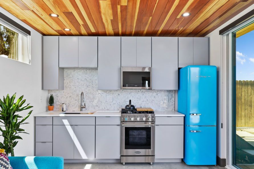 Modern kitchen with gray cabinets, wood ceiling, stainless stove, and bright blue refrigerator