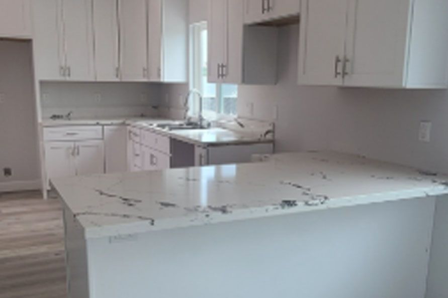 Modern kitchen with white cabinets, marble island countertop, and stainless steel sink
