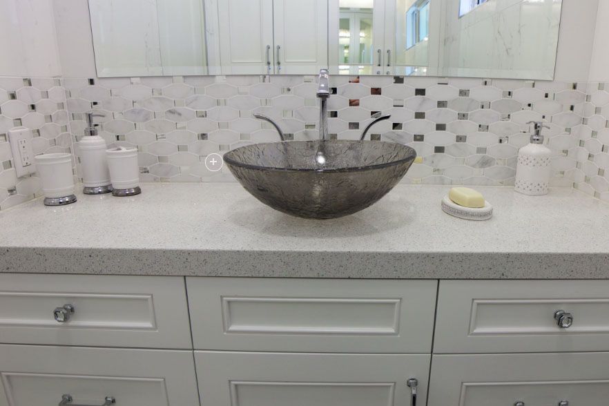 Modern bathroom vanity with double sinks, mosaic backsplash, and a glass vessel basin centered on the counter