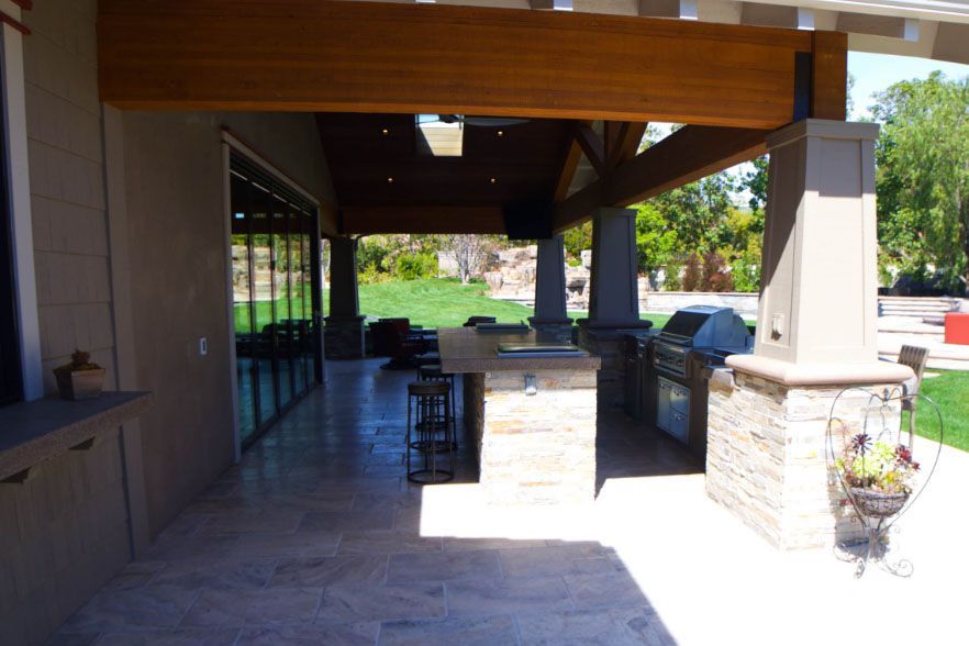 Covered outdoor patio with stone columns, seating, and a view of the garden beyond