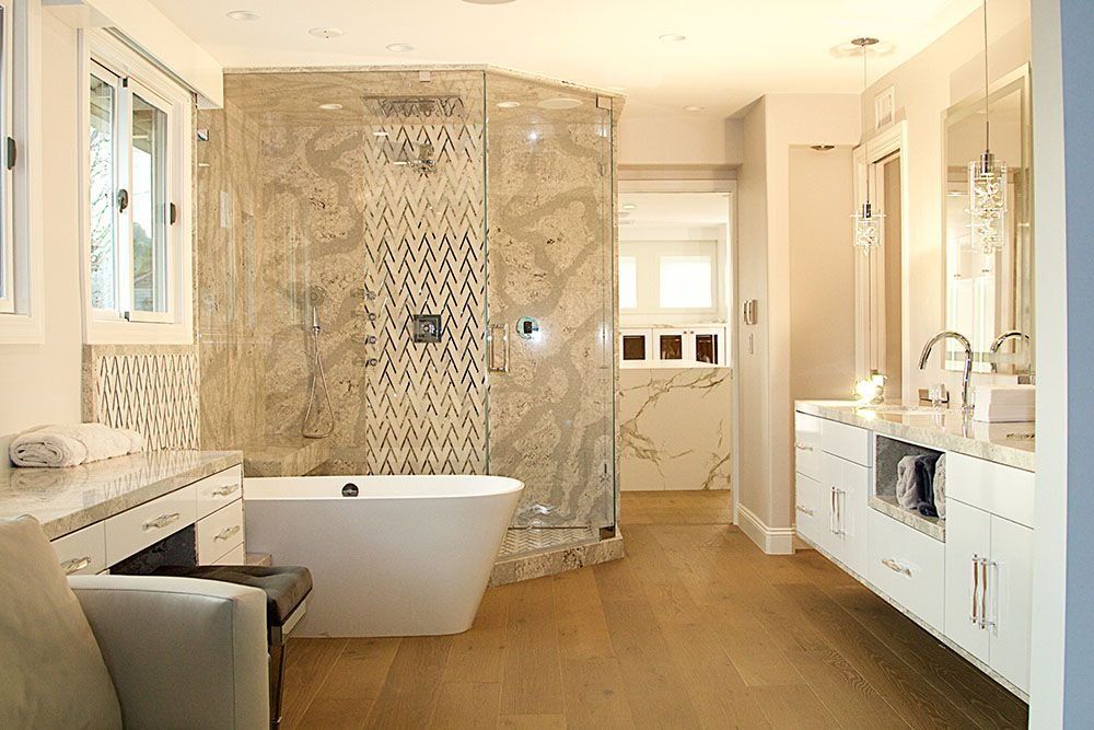 A luxurious, light-filled bathroom with a white freestanding tub, a large glass-enclosed shower, and a modern vanity.