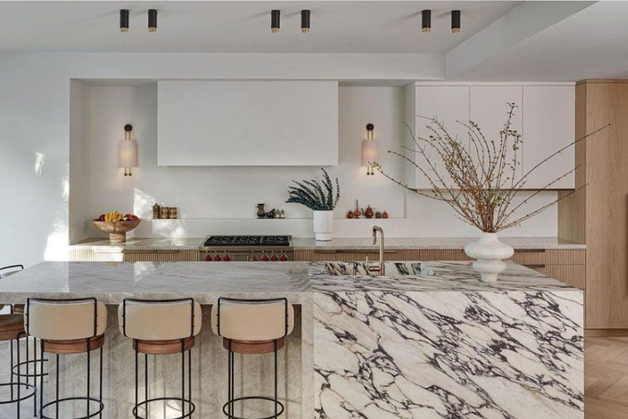 Modern kitchen with marble island, barstools, pendant lights, and minimalist decor