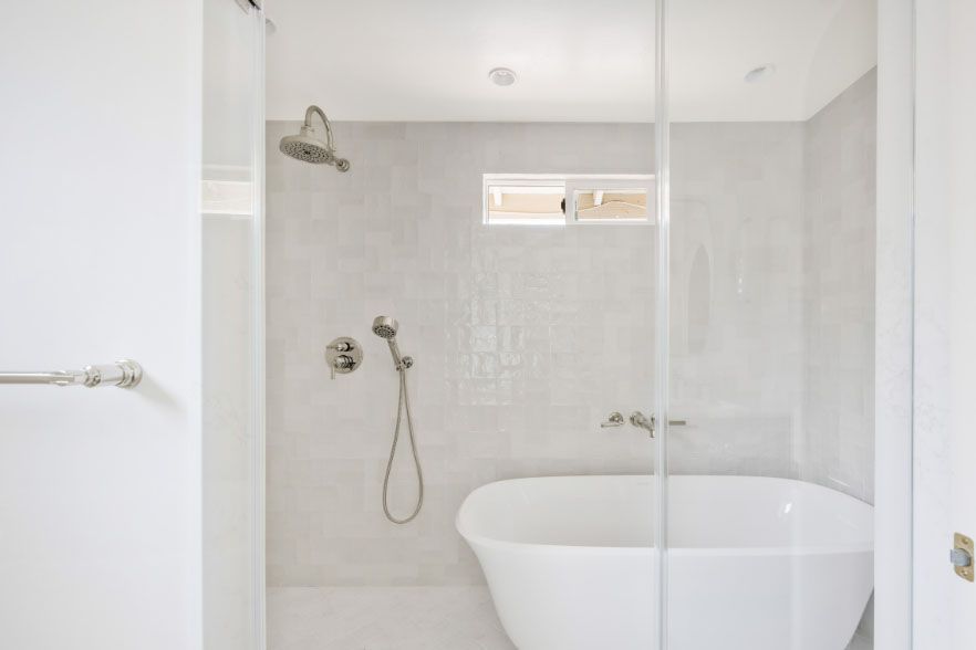 Modern white bathroom with a walk-in shower, freestanding tub, and tiled walls