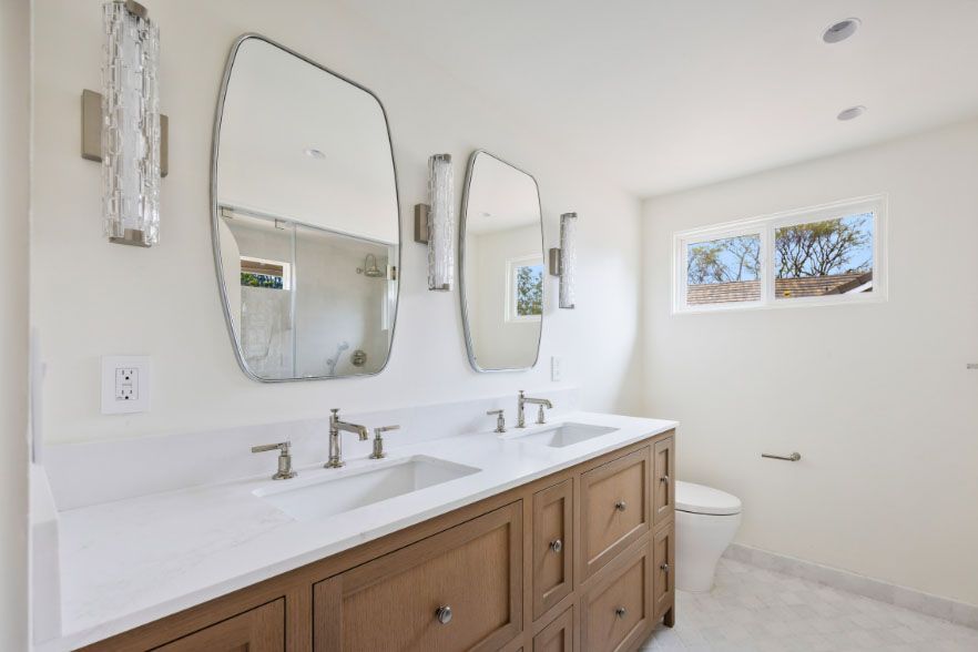 Bright modern bathroom with double sink vanity, mirrors, and small window