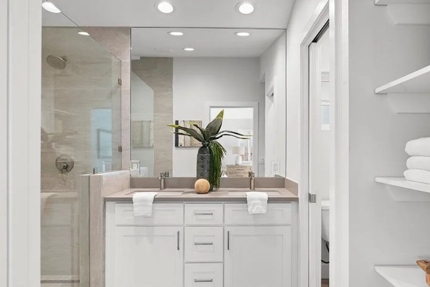 Bright modern bathroom with double vanity, large mirror, and white towels on shelves