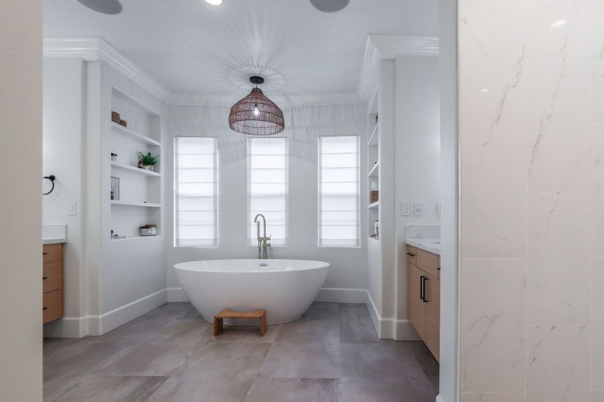 Bright white modern bathroom with a freestanding tub, pendant light, and built-in shelves