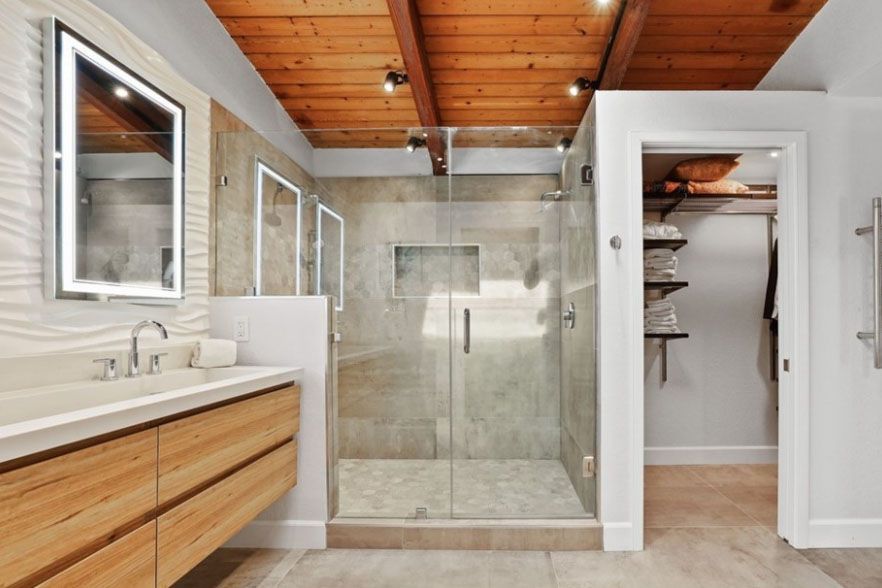 Modern bathroom with glass walk-in shower, wood ceiling, vanity, and open linen closet