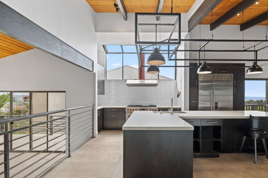 Modern open-plan kitchen with island, pendant lights, and large windows overlooking a city view