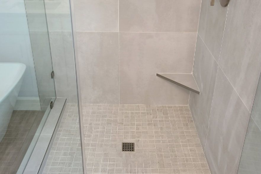 Accessible walk-in shower with beige tile, glass partition, and grab bar.