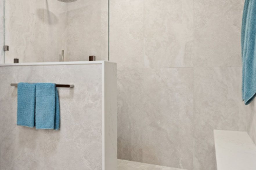 Modern bathroom with white tile, blue towels, and shower curtain