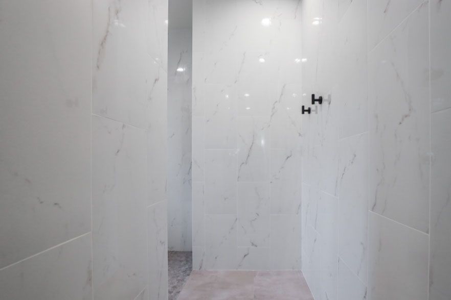 Marble-tiled bathroom shower area with unfinished wall fixture openings