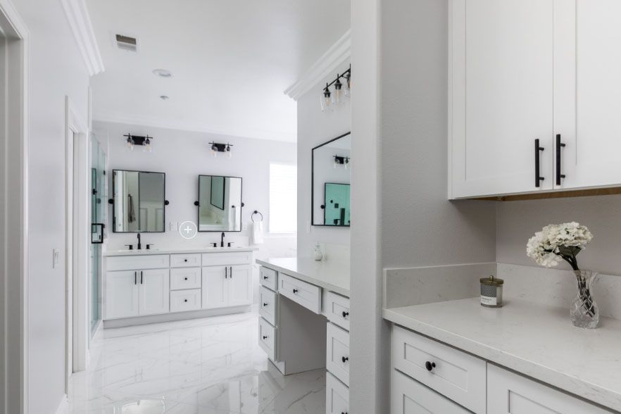 Bright white modern bathroom with dual vanities, mirrors, cabinets, and gray accents
