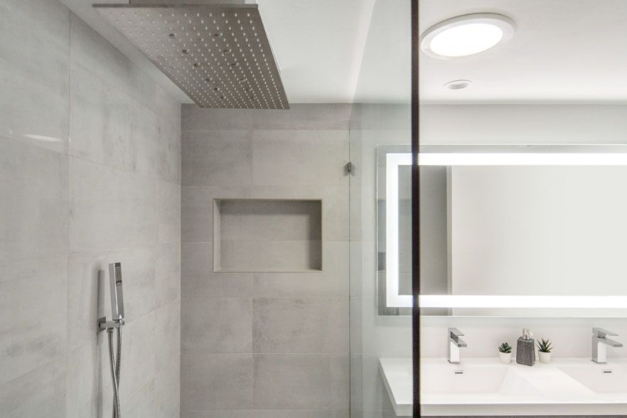 Modern bathroom with a glass shower, rain showerhead, wall niche, and vanity mirror.