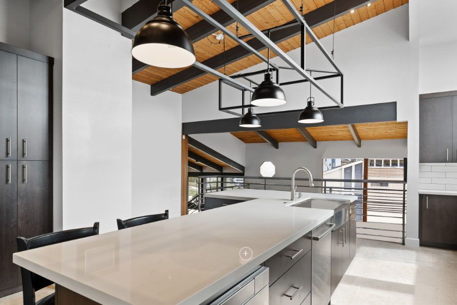 Modern kitchen with large island, stainless-steel appliances, and exposed wood ceiling beams