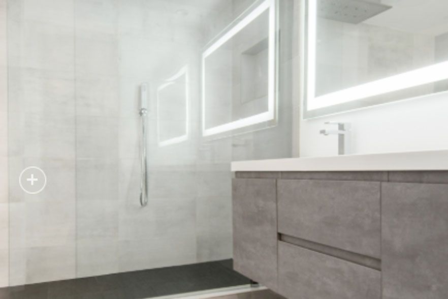 Modern bathroom with glass shower, wall mirror, and gray vanity in a bright, minimalist design