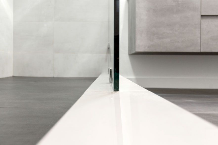 Close-up of a glass divider meeting a white tabletop in a modern interior