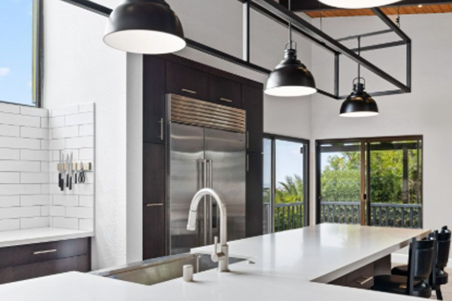 Modern black-and-white kitchen with island, pendant lights, stainless steel appliances, and large windows
