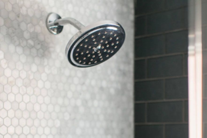 Chrome showerhead against a tiled bathroom wall