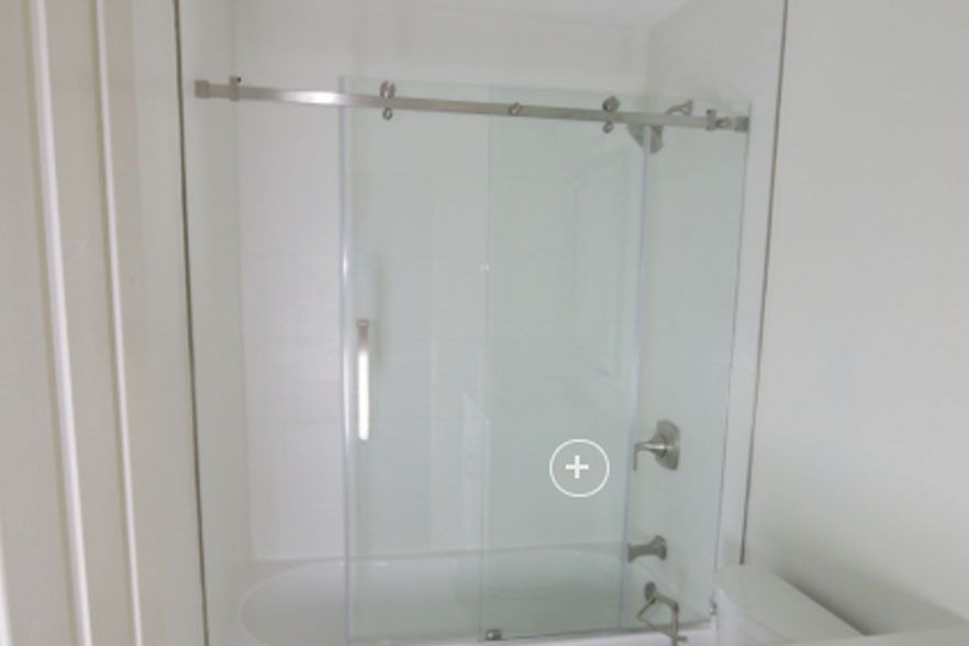 Glass shower enclosure with chrome fixtures in a white bathroom