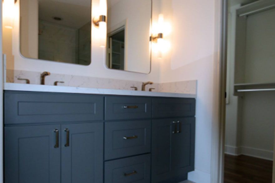 Blue bathroom vanity with double mirrors, sink, and wall sconces