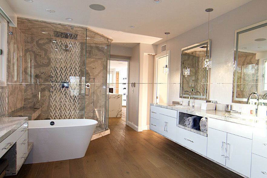 Bright modern bathroom with freestanding tub, glass shower, white vanity, and wood floor