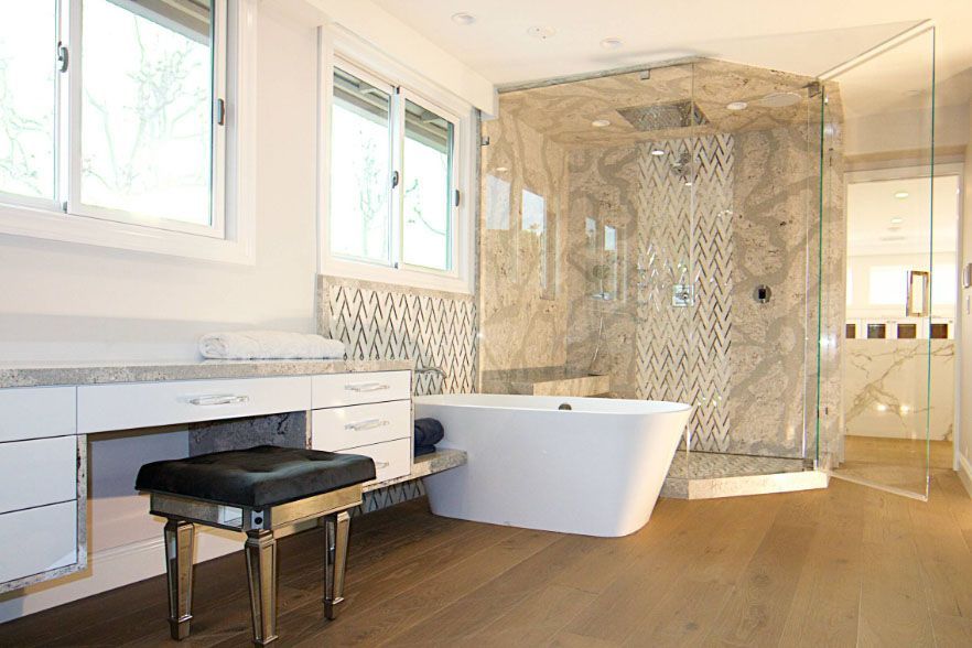 Modern bathroom with white vanity, black stool, freestanding tub, and glass shower enclosure