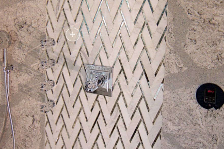 Top-down view of a chevron-patterned walkway with a small metal fixture and a round black object on sand.