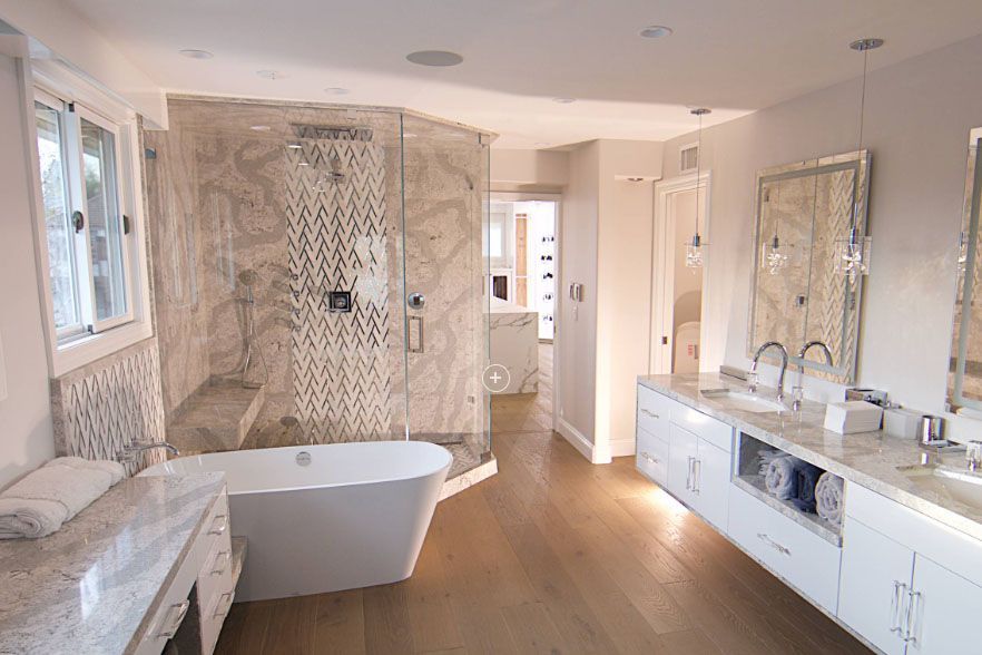 Bright modern bathroom with freestanding tub, large shower, wood floor, and long double vanity with mirrors.