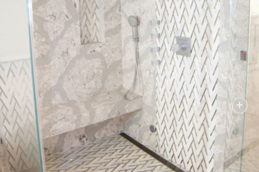 Empty tiled shower stall with bench, wall-mounted showerhead, and drain in a bathroom