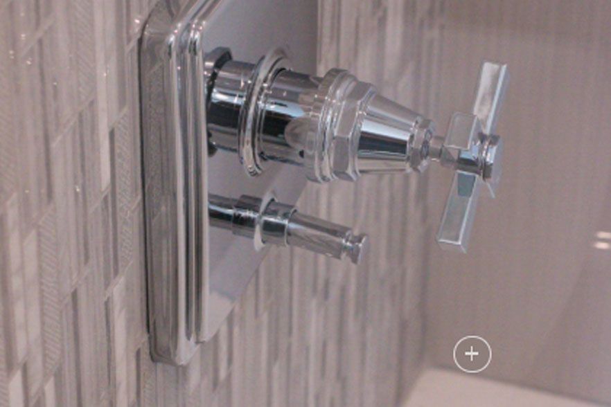 Chrome shower control faucet with handle against tiled bathroom wall