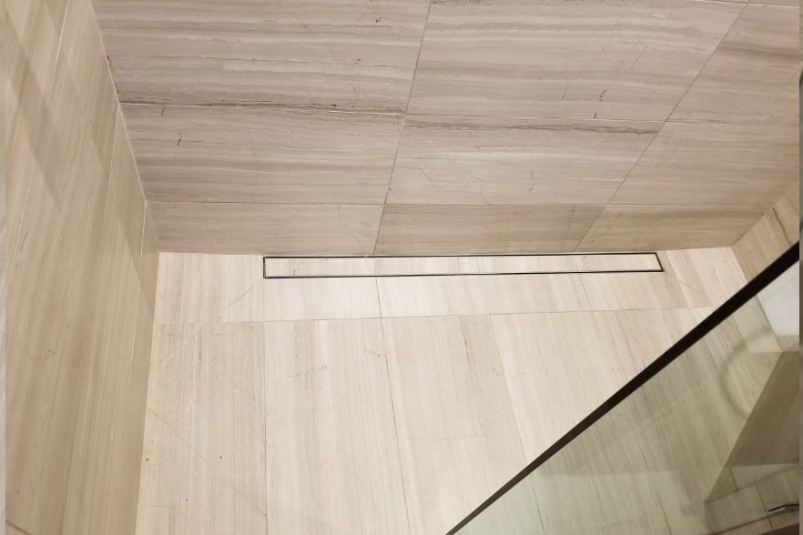 Empty light wood interior with a narrow floor drain and glass panel at right.