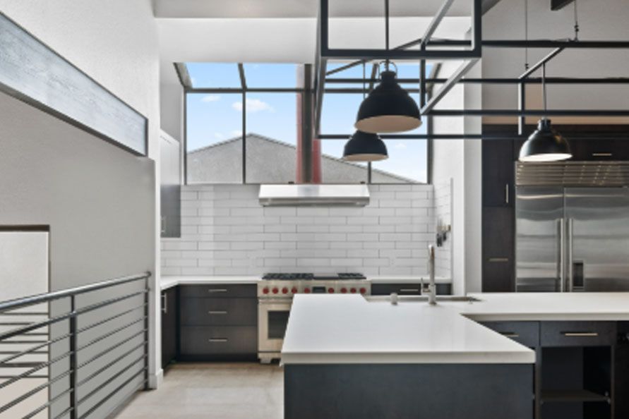 Modern kitchen with white island, black pendant lights, and large windows with a city view