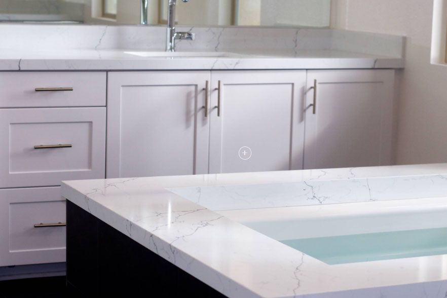 Modern white kitchen with marble countertops and a light blue sink or countertop island
