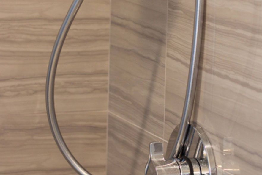 Chrome shower hose and fixture against a wood-paneled shower wall