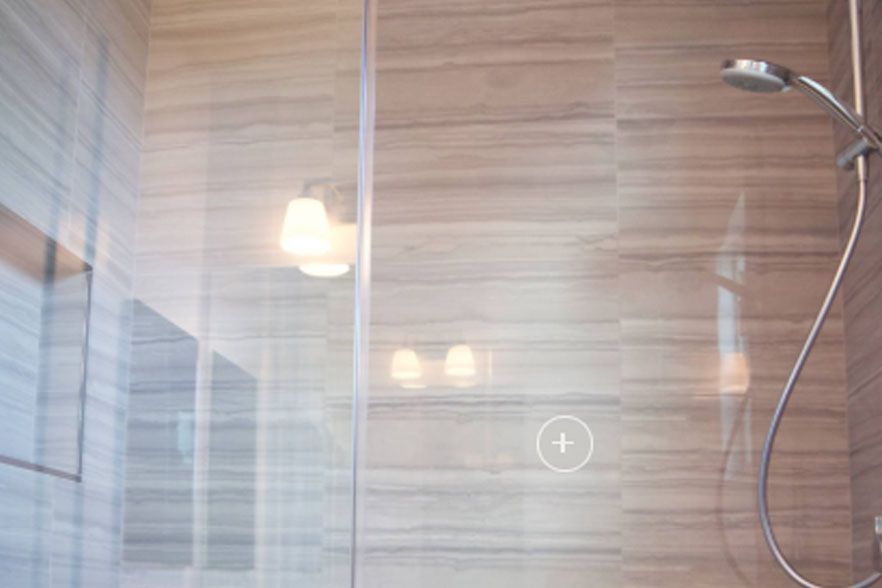Modern bathroom shower with glass partition, wood-look tile walls, and chrome showerhead