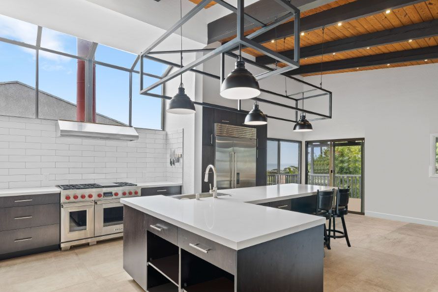 Modern kitchen with island, stainless steel appliances, and high ceilings with pendant lights and skylights