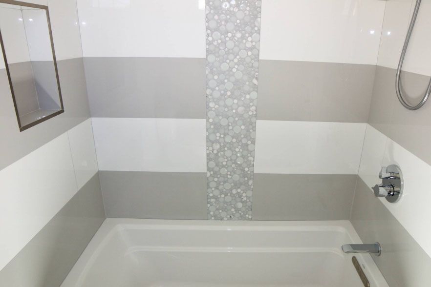 Accessible bathroom with white striped walls and a bathtub with grab bars and shower fixtures.