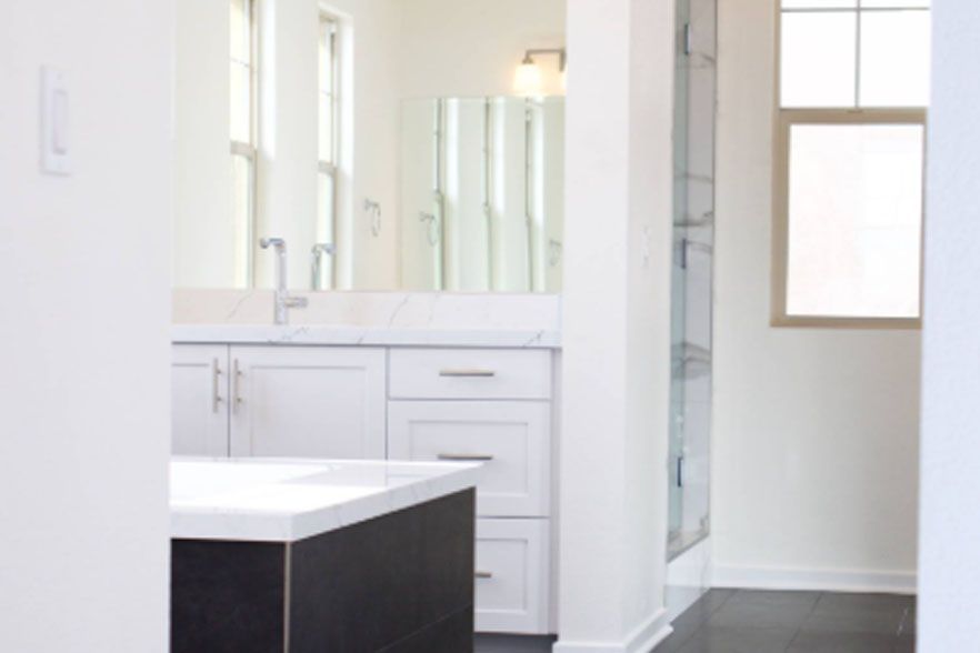 Bright modern bathroom with white vanity, mirrors, and a glass shower door