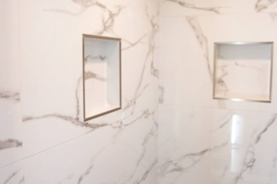 Marble-tiled bathroom wall with two framed mirrors and a white counter edge