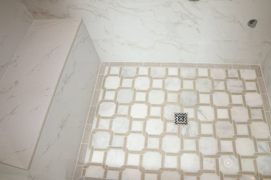 Bathroom shower floor with white tile and a square drain in the center