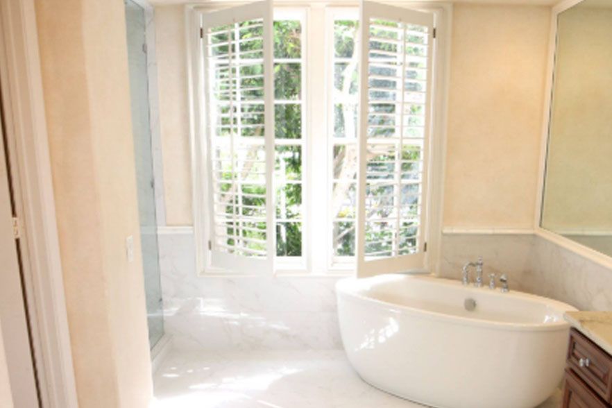 Bright bathroom with a white soaking tub, large window, and cream-colored walls