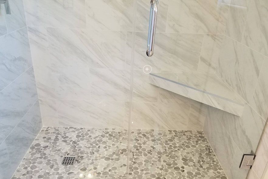 Modern tiled shower with rainfall showerhead and pebble-style floor drain area