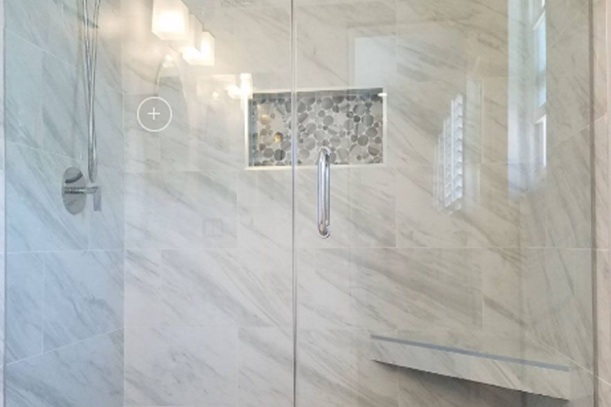 Modern tiled shower with glass door, chrome fixtures, and built-in niche.