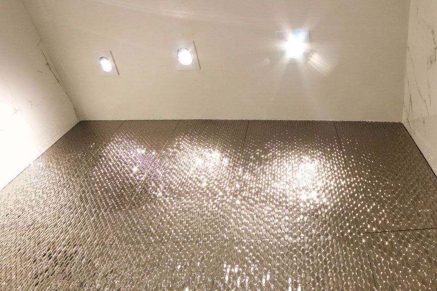 Sparkling mosaic tile wall under three ceiling lights in a white room