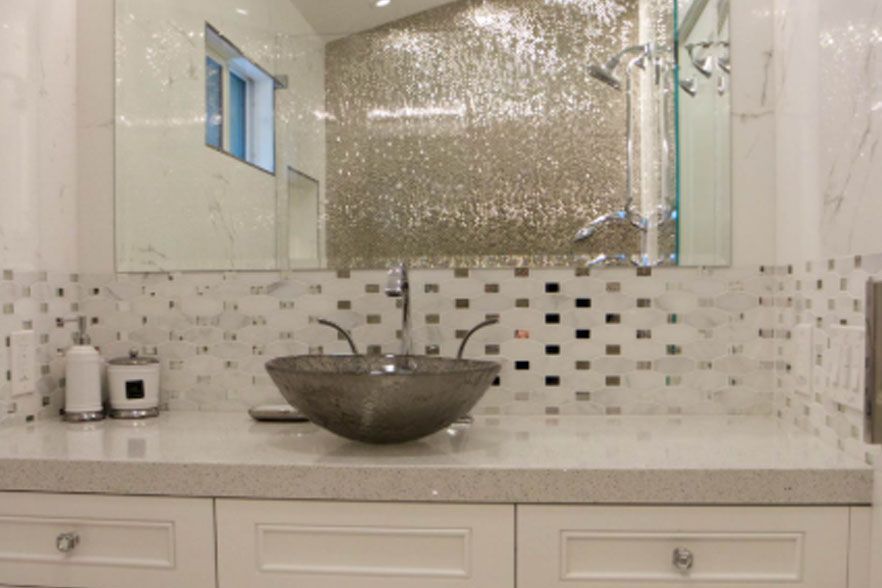 Modern bathroom vanity with mosaic mirror, white cabinets, and a stone vessel sink.