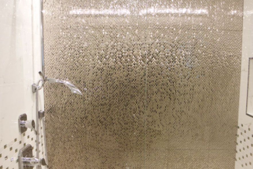 Shower with glass door covered in water droplets and a chrome handle on the left.